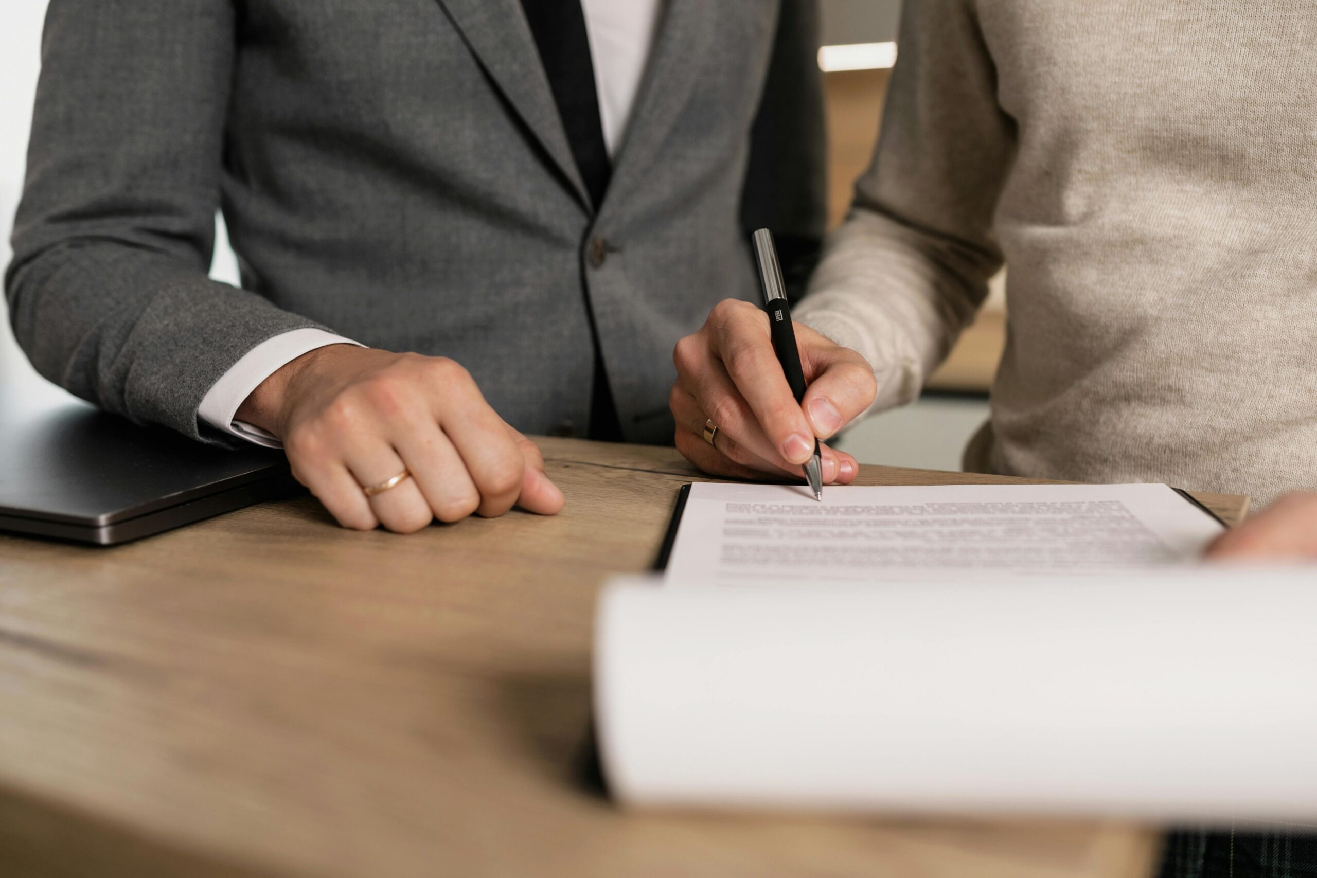 Image of two people signing a contract. Learn about fees when financing an investment property in Maryland.